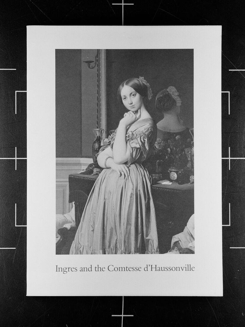 A black and white film photograph of a book titled “Ingres and the Comtesse d’Haussonville” in front of a geometric grid.